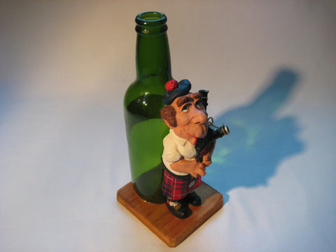 Vintage quirky fun bottle with figurine of a Scottish Bagpipe player (Angus MacFlasher) in front of the bottle